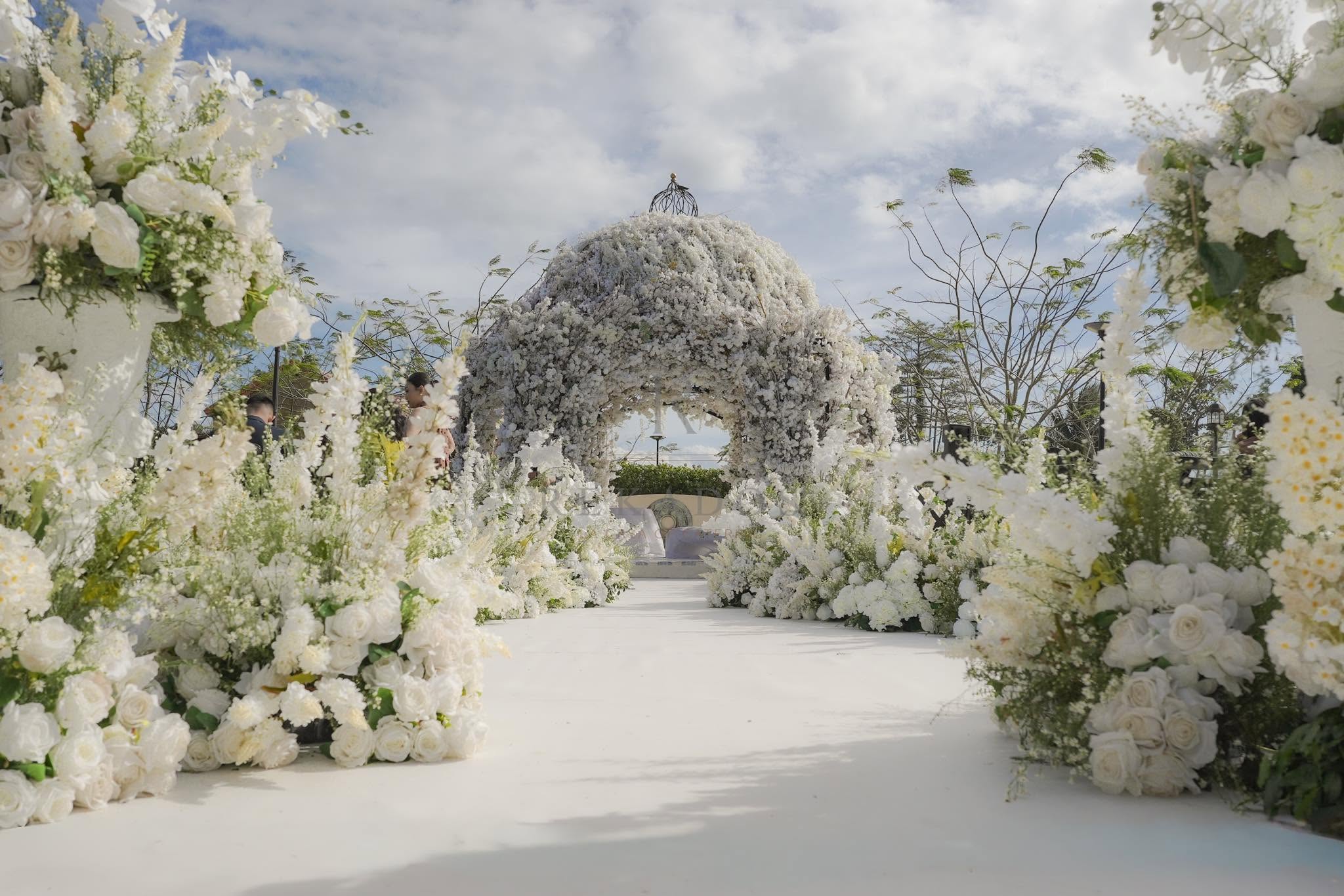 All-white floral ceremony arch built by Rekados' La Casa of Catering
